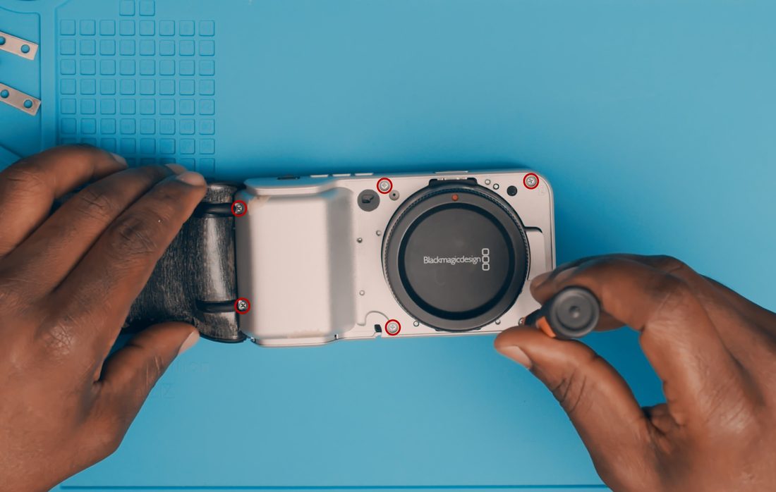 Lay the camera on its back. Lift the rubber cover to expose the chassis screws. Remove those screws, the rubber flap can remain attached.