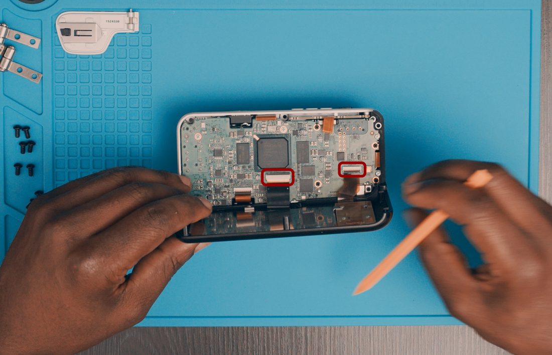 Lift the rear cover to expose the main board. Release or flip the FPC locking tabs and withdraw the cables.