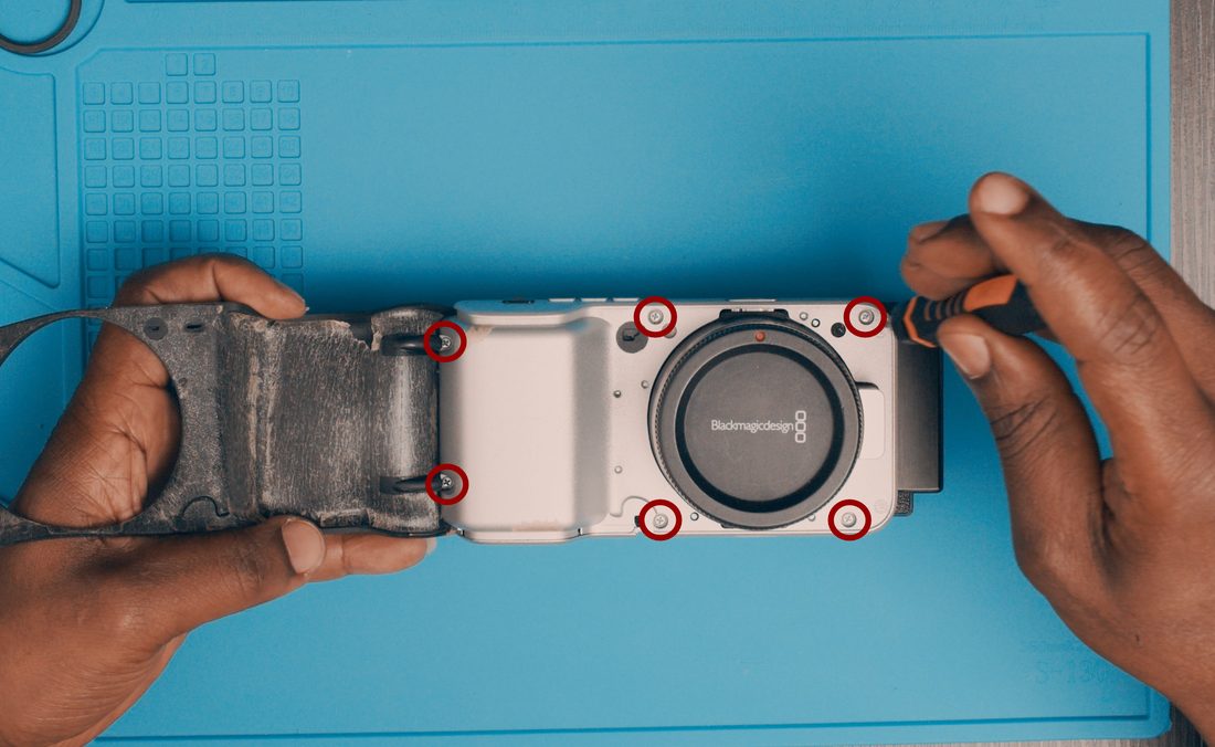 Carefully place the camera facing up to expose the securing screw holes. Fit the remaining body screws. Press the rubber cover back into place.